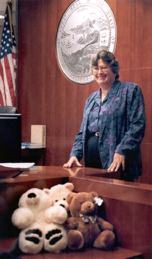 Judge Donna Hitchens stands behind the teddy bears she hands out to young witnesses who testify in her courtroom.